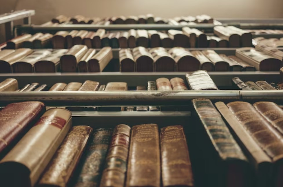 various old books in hardcover format standing on bookshelves