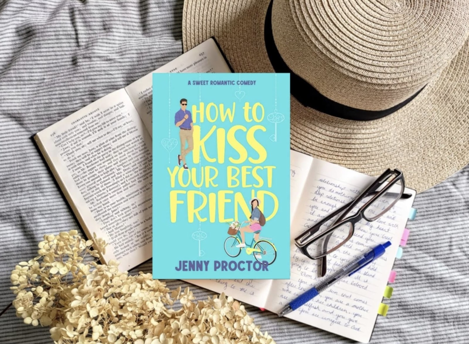 Book "How to Kiss Your Best Friend" on a notepad with a pen and a hat