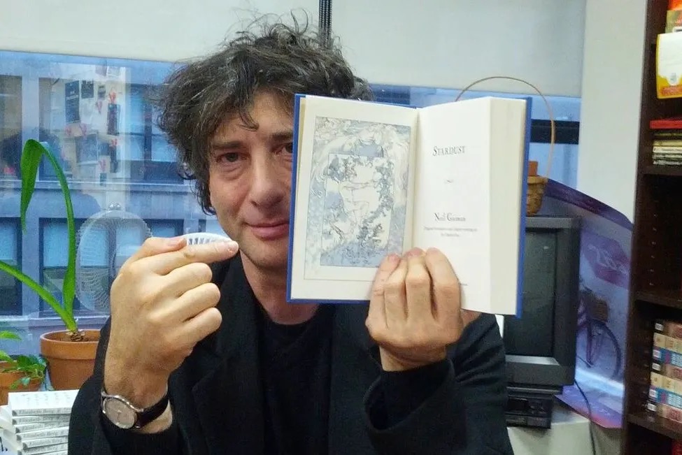 Neil Gaiman holding a book