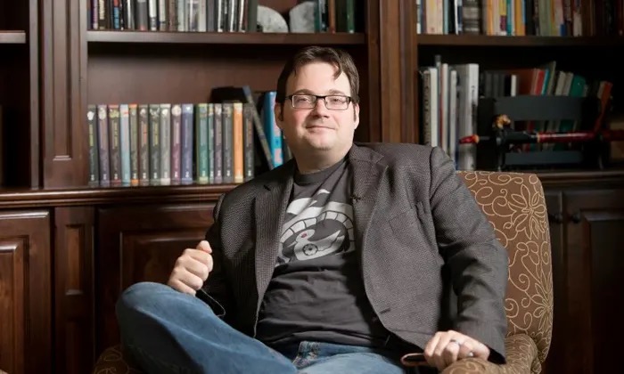 Brandon Sanderson sits with books in the background